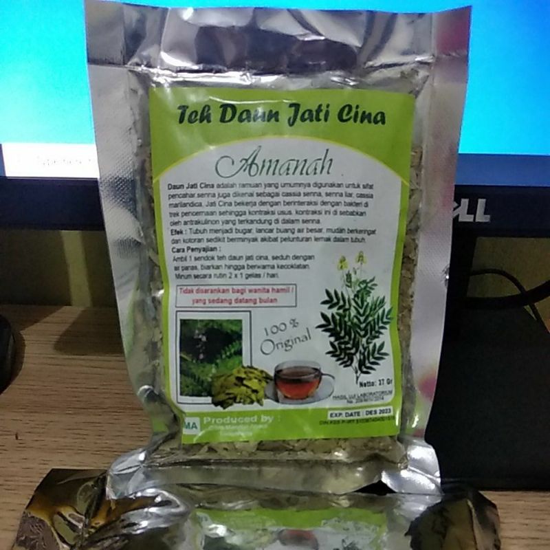 Jati Cina teh dalam cangkir dengan daun dan bunga di latar belakang